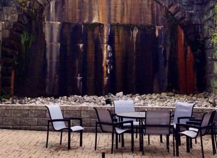 a table and chairs under a stone bridge