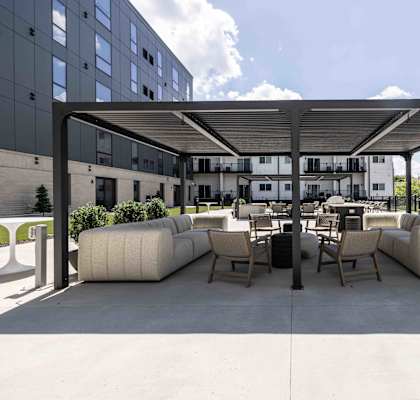 A modern outdoor seating area with white cushioned furniture and a black metal roof.