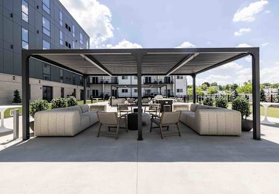 A modern outdoor seating area with white cushioned furniture and a black metal roof.