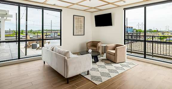 a living room with couches and chairs and large windows at The Standard on 32nd, West Fargo, North Dakota
