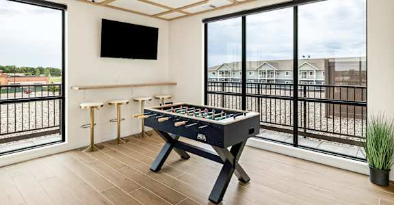 a game room with a foosball table and a large window at The Standard on 32nd, West Fargo, 58078