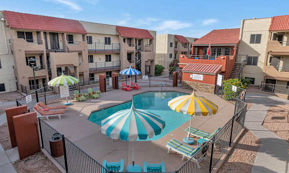 Three people are sitting on the edge of a pool with water splashing around them.