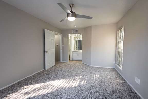 A room with a ceiling fan and carpeted floor.