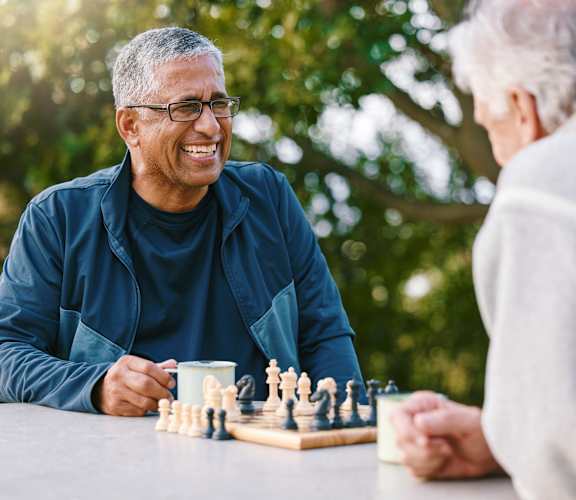 Two people playing chess outdoors.