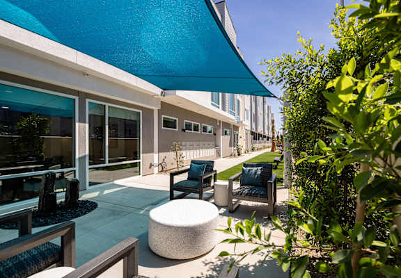 A patio with a blue umbrella and a white table.