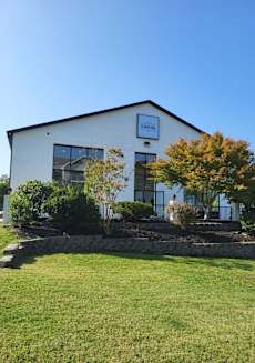 the front of a white building with a lawn and trees at Schaefer Ridge Apartments, Branson
