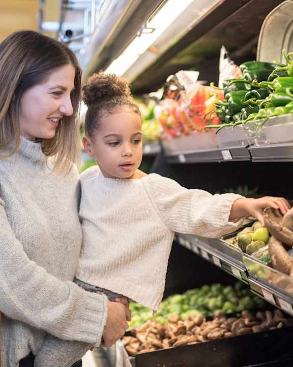 A woman and a child are shopping for produce.