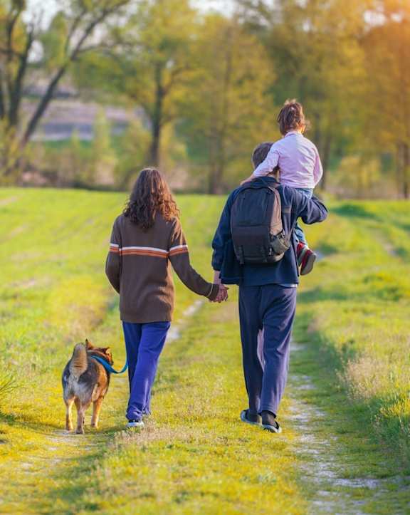 A woman, a man and a child are walking a dog on a path.