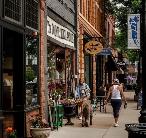 a woman walking a dog down a street at One West Drive Apartments, Excelsior, Minnesota