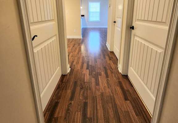 a hallway with wooden floors and white doors
