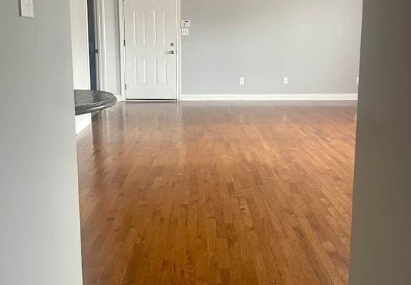 an empty living room with wood floors and a ceiling fan