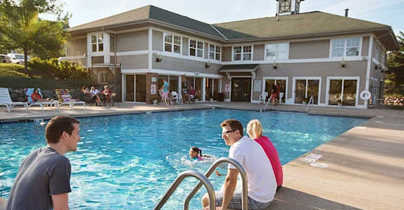 a group of people sitting at a pool with a building in the background