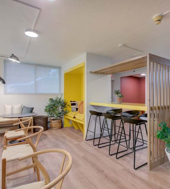 A room with a yellow door and a bar area with stools.