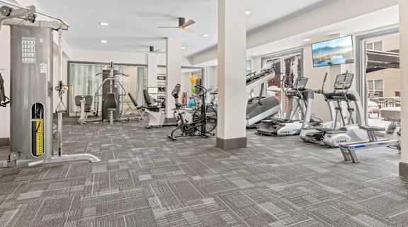 a gym with exercise equipment and a tv in the corner at Aster Apartments, Beachwood
