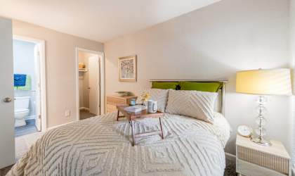 A bedroom with a large bed and a nightstand with a lamp.
