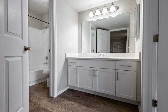A white bathroom with a vanity and a mirror.