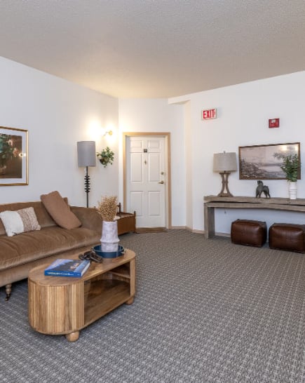 A hallway with a table and chairs and a mirror on the wall. at Eighth Street Manor  Apartments, Fargo, ND