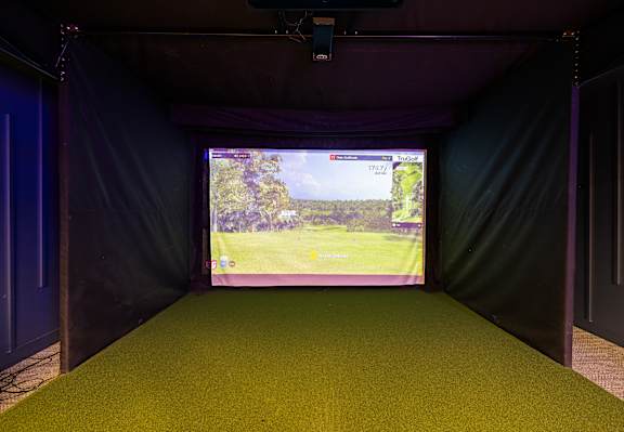 A screen in a dark room shows a golf course.