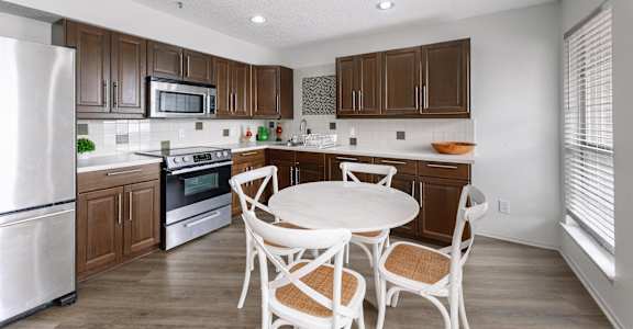 a kitchen with wooden cabinets and a white table and chairs