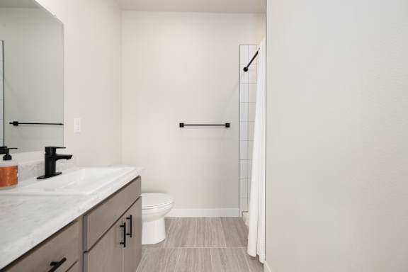 A white bathroom with a toilet, sink, and a mirror.