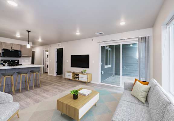 A modern living room with a grey couch, a wooden coffee table, and a flat-screen TV.