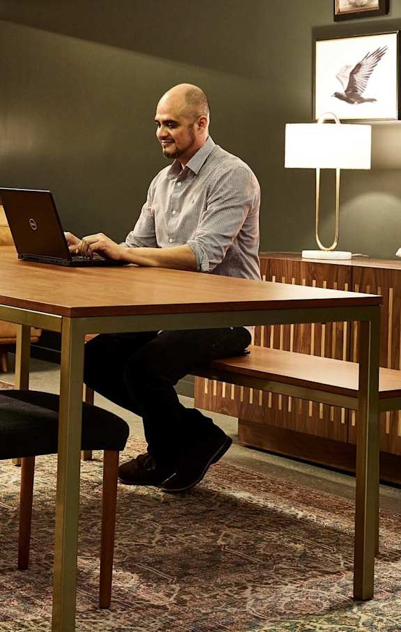 A man is sitting at a desk using a laptop.