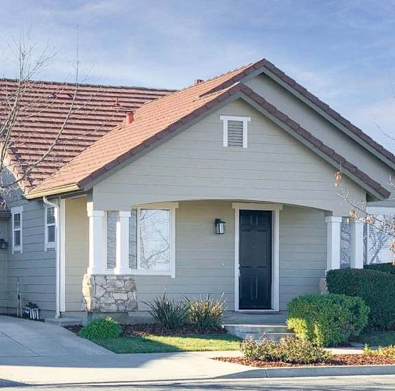 A house with a grey siding and a brown roof.