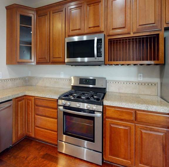 A kitchen with wooden cabinets and a stainless steel oven.