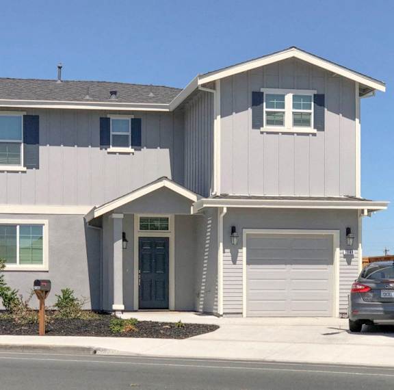 A modern house with a grey and white exterior and a grey car parked in front.
