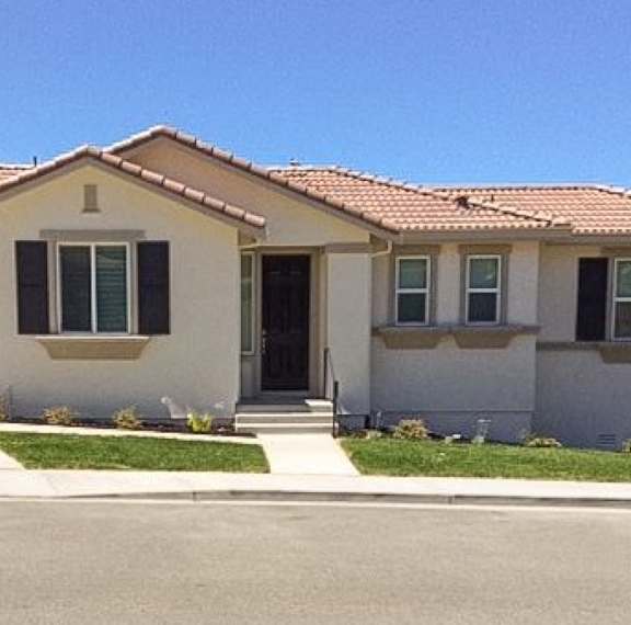 A house with a brown roof and white walls has a black door and windows.