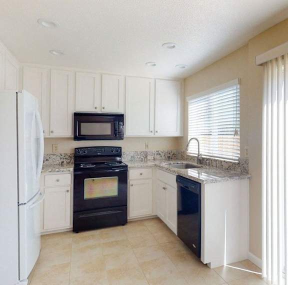 A kitchen with black appliances and white cabinets.