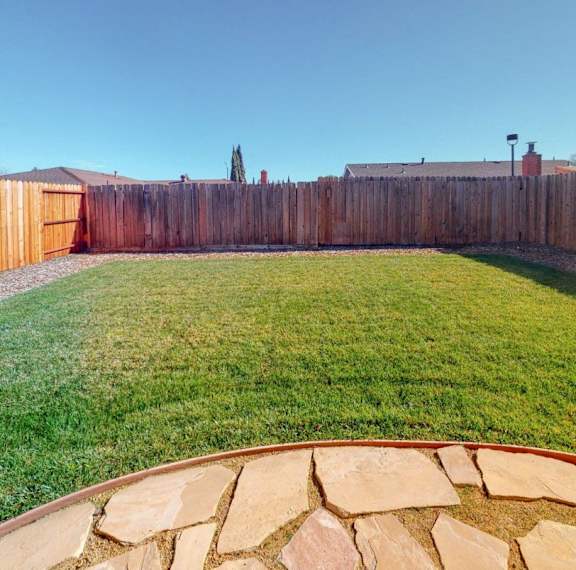 A backyard with a wooden fence and a stone pathway.
