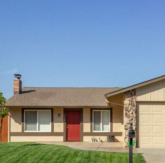 A house with a red door and a mailbox in front.