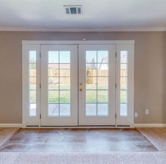 A pair of white double doors with glass panels and sidelights.