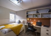 Thumbnail 1 of 8 - a bedroom with a bed and a desk with a laptop