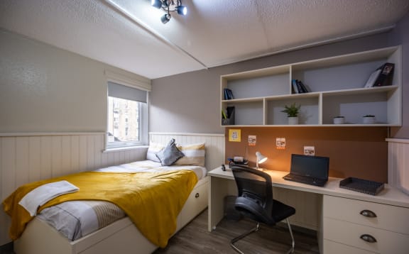 a bedroom with a bed and a desk with a laptop