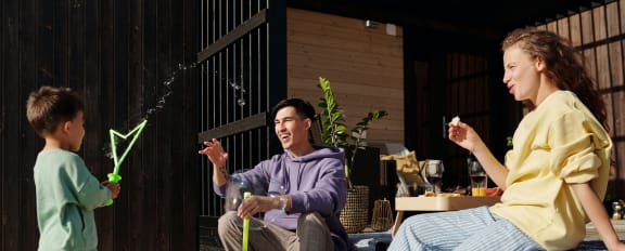 a man and a woman sit on the steps of a house while a young boy plays with