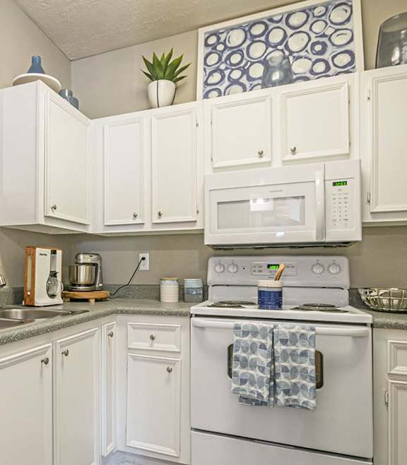 A white kitchen with a white oven and white cabinets.
