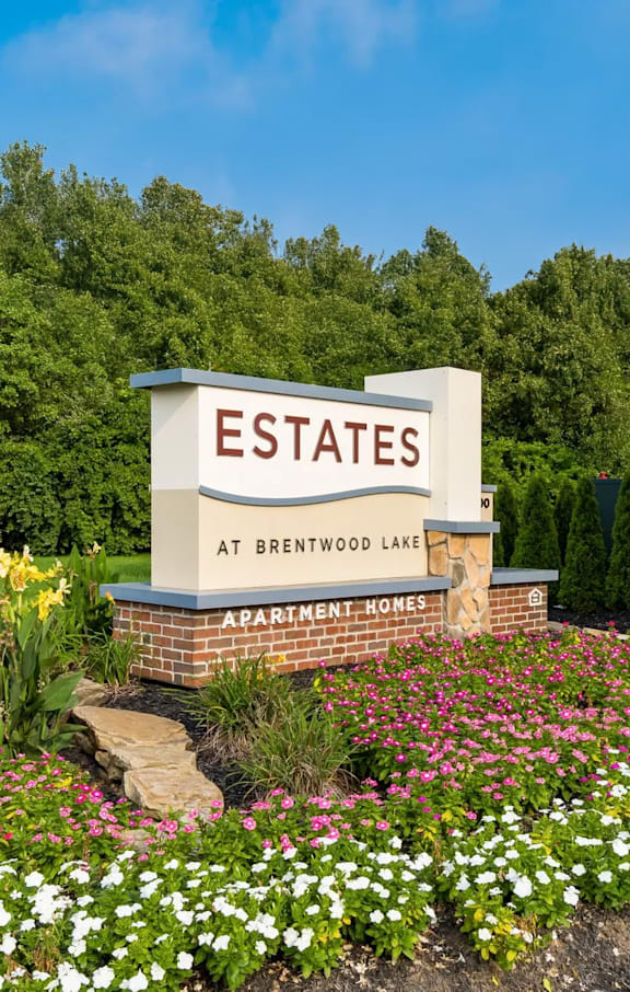 A sign for Estates at Brentwood Lake with a flower bed in front.