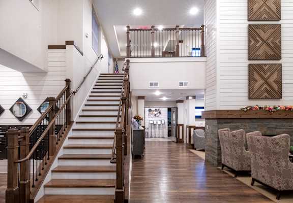 a living room with a staircase and a dining room with chairs