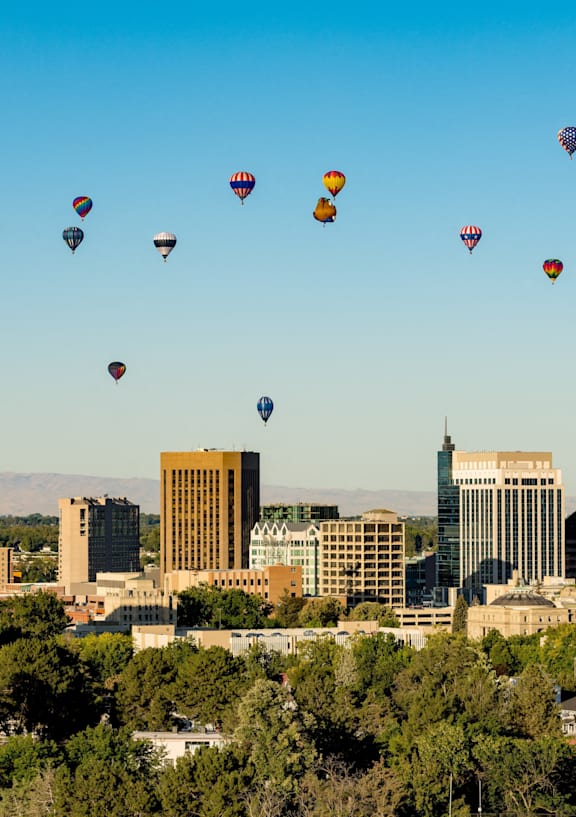 A cityscape with a large number of hot air balloons flying in the sky.