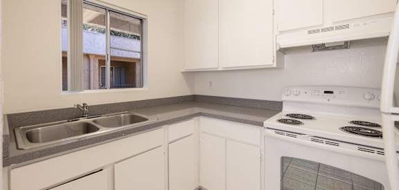 A kitchen with white cabinets and a stove top oven.