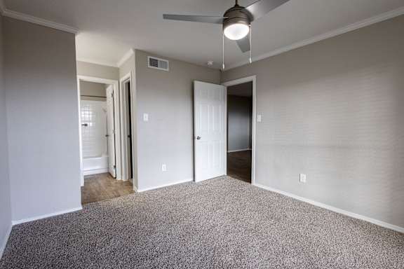 A room with a ceiling fan and carpeted floor.