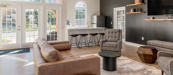 A living room with a brown couch, a grey armchair, and a black coffee table.