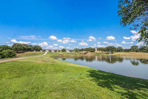 A serene landscape with a lake, trees, and a clear sky.