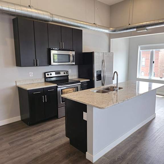 A kitchen with black cabinets and a granite countertop.