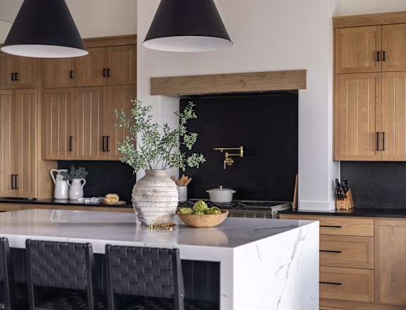 A kitchen with wooden cabinets and black pendant lights.