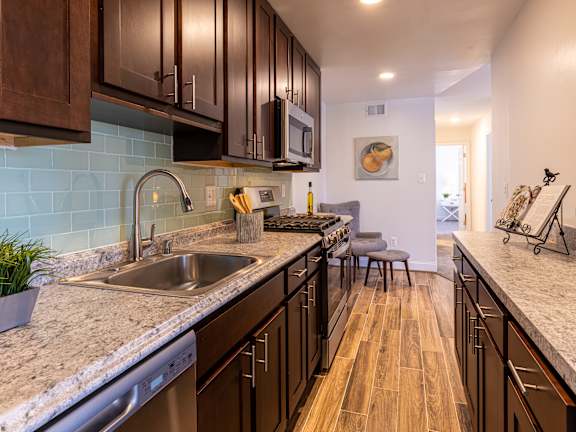 A kitchen with brown cabinets and a blue tile backsplash.
