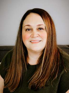 A woman with long brown hair wearing a green top.