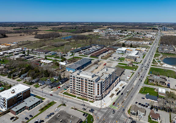 A large building is in the middle of a road and a parking lot.